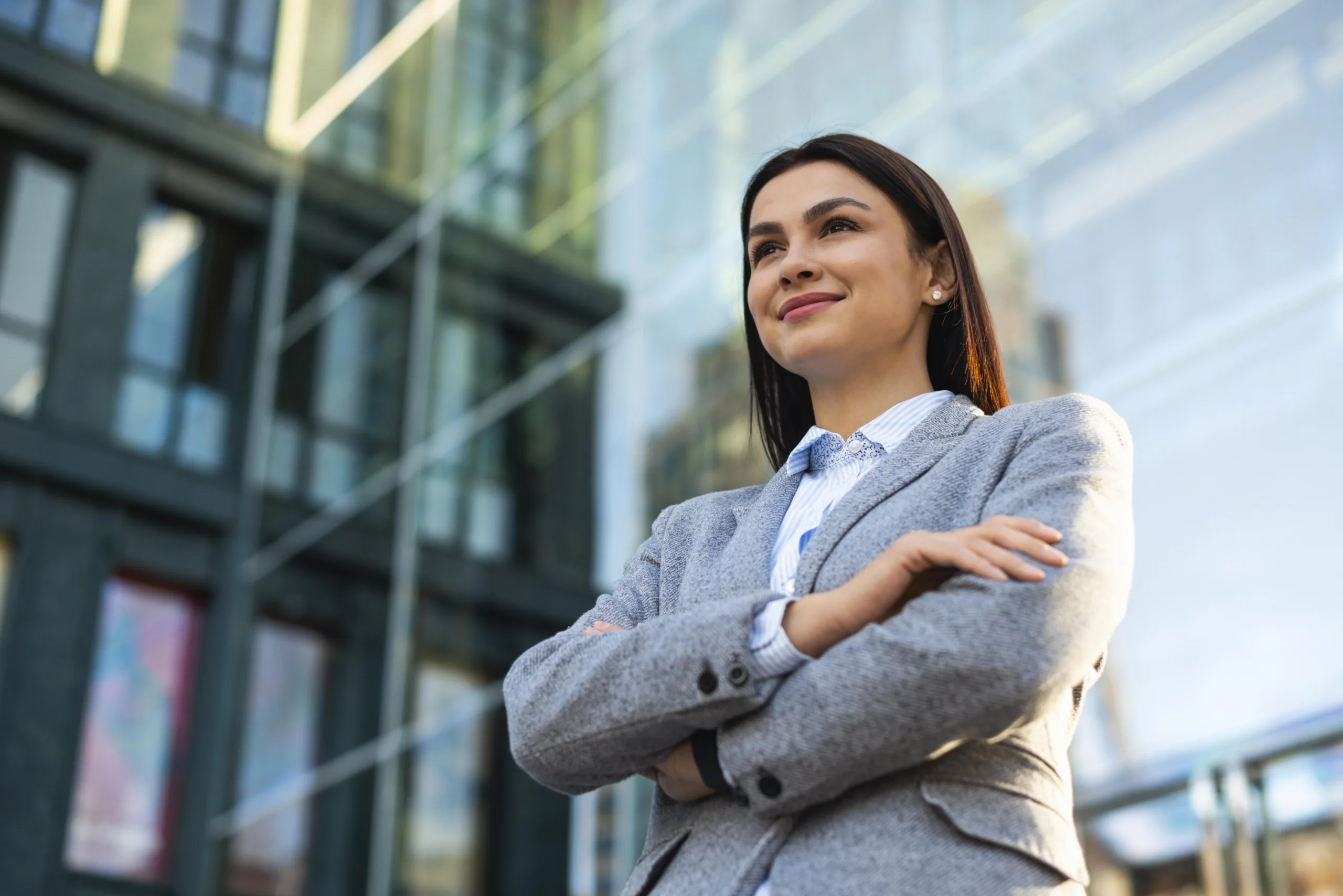 low-angle-businesswoman-posing-with-arms-crossed-city low-angle-businesswoman-posing-with-arms-crossed-city